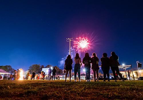 校友 watching fireworks on football field.